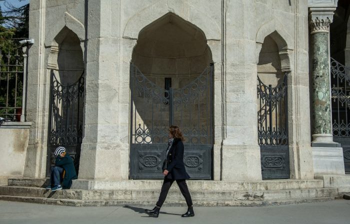 person in suit jacket walking on front of black gate